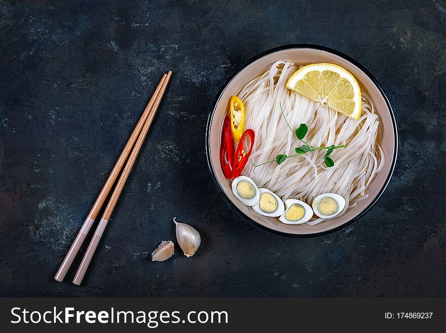 Rice noodles Asian cuisine with quail eggs, chili pepper and lemon, and green pea sprout