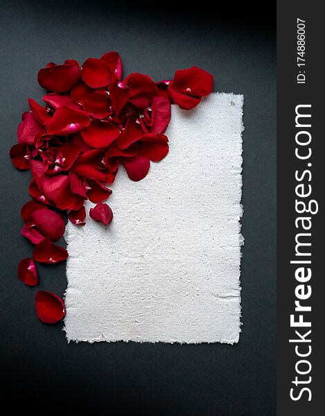 Beautiful frame of red rose petals with place for text. Handmade paper sheet, textured surface. Greeting card for the holiday.