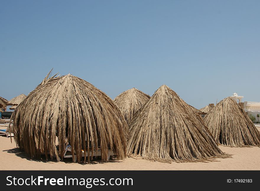 Tents from leaves of palm trees cost on a beach at the sea