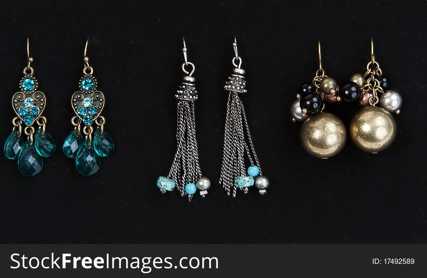 Three pairs of women's earrings on a dark fabric background