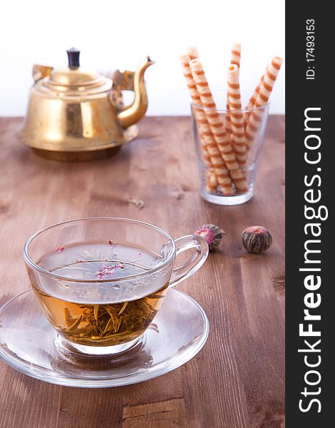 Transparent cup of green tea with old teapot and wafers