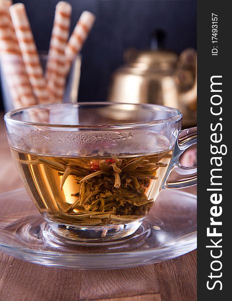 Transparent cup of green tea with old teapot and wafers