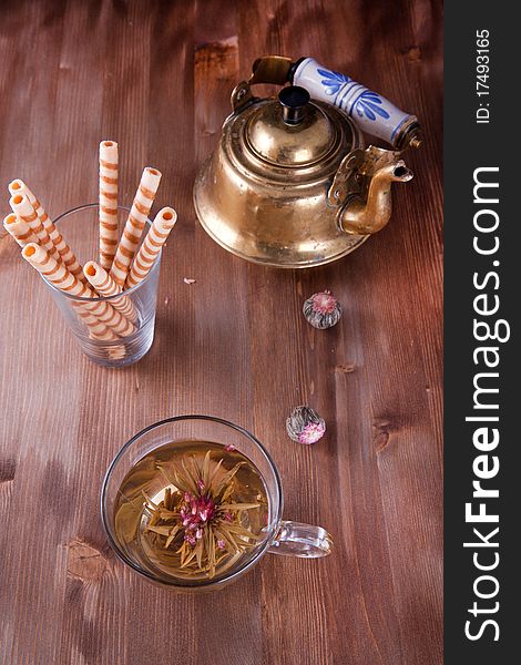 Transparent cup of green tea with old teapot and wafers