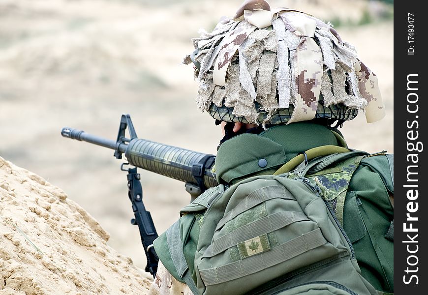 Soldier in desert uniform aiming his rifle