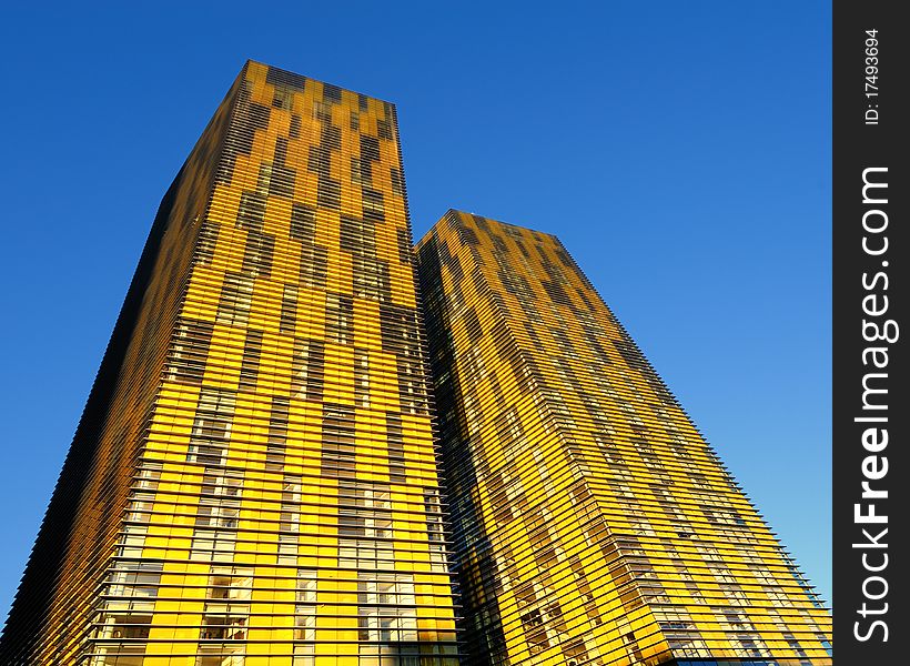 A pair of modern orange condominiums tower into the clear blue sky. A pair of modern orange condominiums tower into the clear blue sky