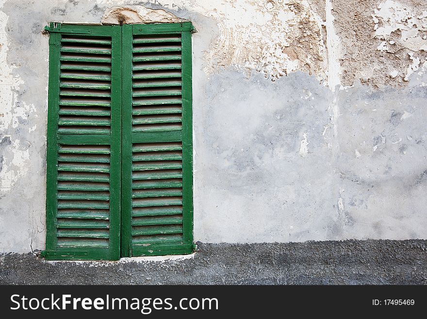 Old-fashioned window with green closed shutters (traditional building in a town on Majorca island in Spain)