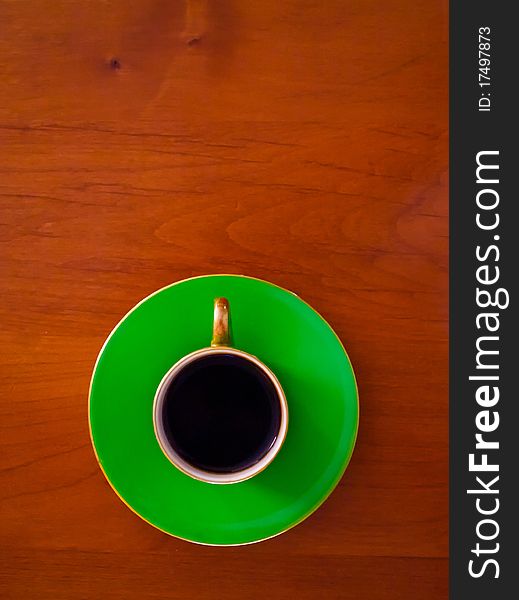 A green cup and saucer on a table holding a shot of espresso. A green cup and saucer on a table holding a shot of espresso.