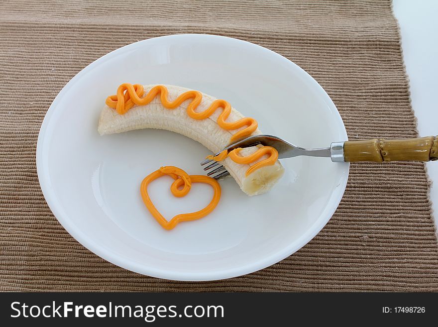 Banana with easy spread cheese and fork on white plate. Banana with easy spread cheese and fork on white plate.