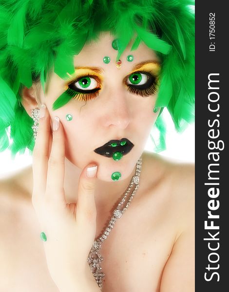 Beautiful young woman wearing artistic make-up with green feathers, beads. Beautiful young woman wearing artistic make-up with green feathers, beads.