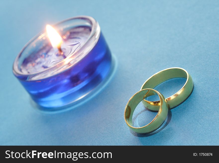 Gold wedding rings with blue burning candle. Gold wedding rings with blue burning candle