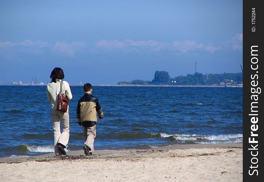 A mother and a son walking on the beach in early spring. A mother and a son walking on the beach in early spring