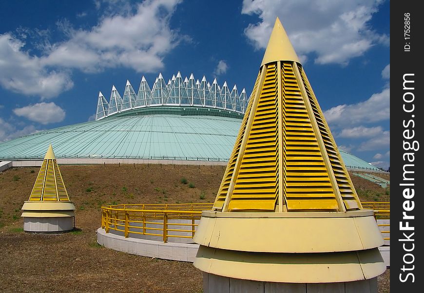 Yellow cones, blue sky with an amazing building