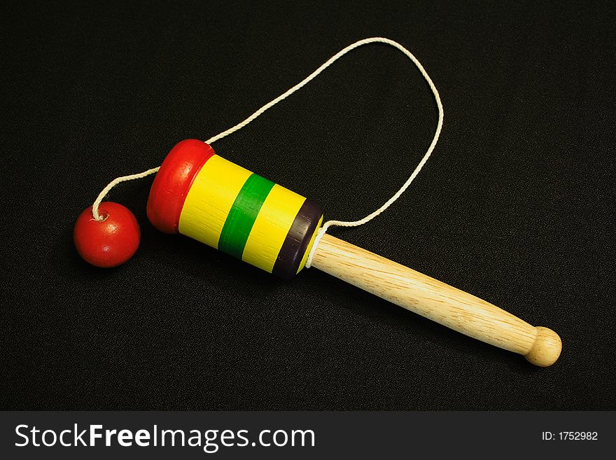 This child's ball and cup toy is perfectly set against a black background. This child's ball and cup toy is perfectly set against a black background.