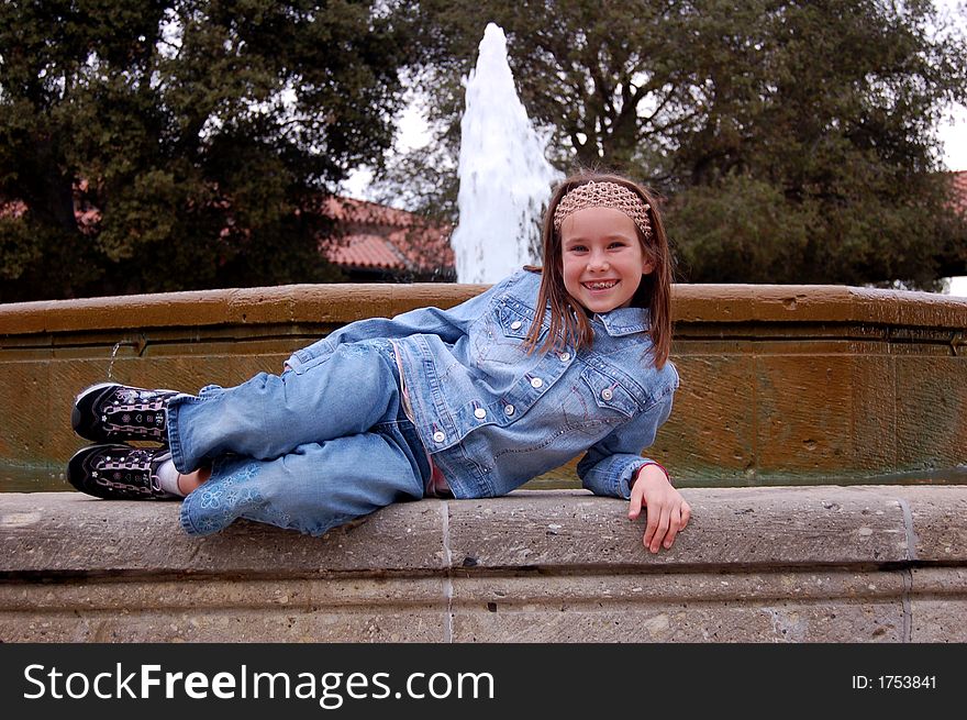 A pretty nine year old girl lying down in front of a fountain. A pretty nine year old girl lying down in front of a fountain.