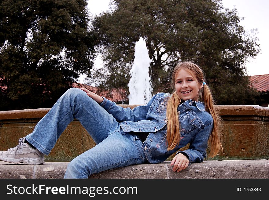 A pretty eleven year old girl lying down in front of a fountain. A pretty eleven year old girl lying down in front of a fountain.