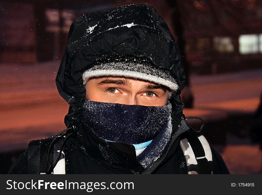 Portrait of the young guy, wrapped up in a bright scarf, which walks on city during a snowfall. Portrait of the young guy, wrapped up in a bright scarf, which walks on city during a snowfall