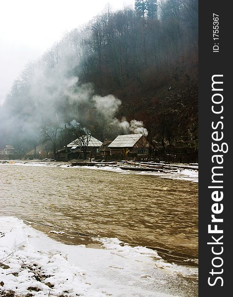 Golden muddy mountain river near houses. Golden muddy mountain river near houses