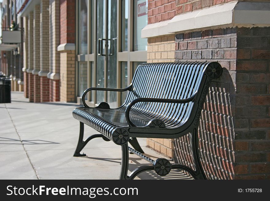 An Empty iron bench on city sidewalk. An Empty iron bench on city sidewalk