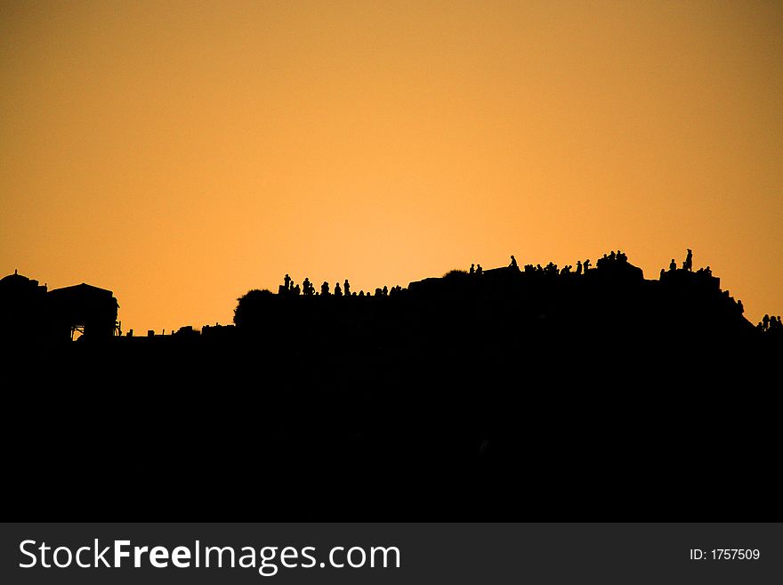 People silhouetted against the sunset along the cliff Santorini