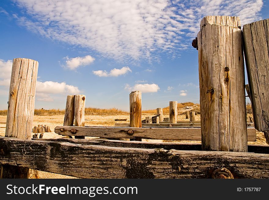 The weatherbeaten, worn remains of wooden pilings that used to support an abandoned pier and boardwalk on the beach. The weatherbeaten, worn remains of wooden pilings that used to support an abandoned pier and boardwalk on the beach.