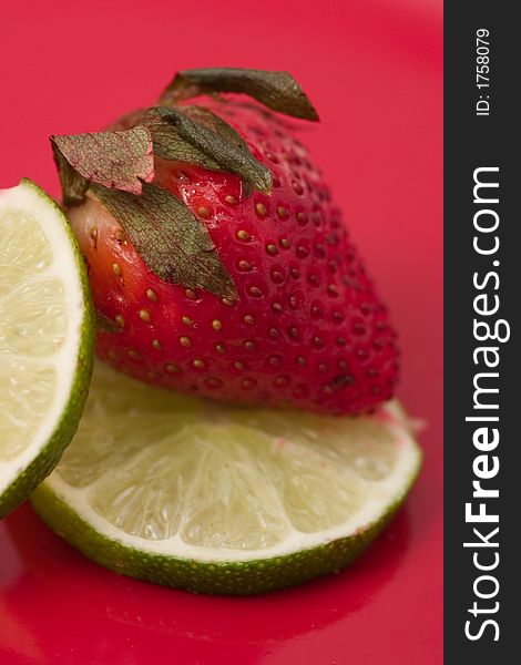 Strawberry and slices of lime on red background. Strawberry and slices of lime on red background