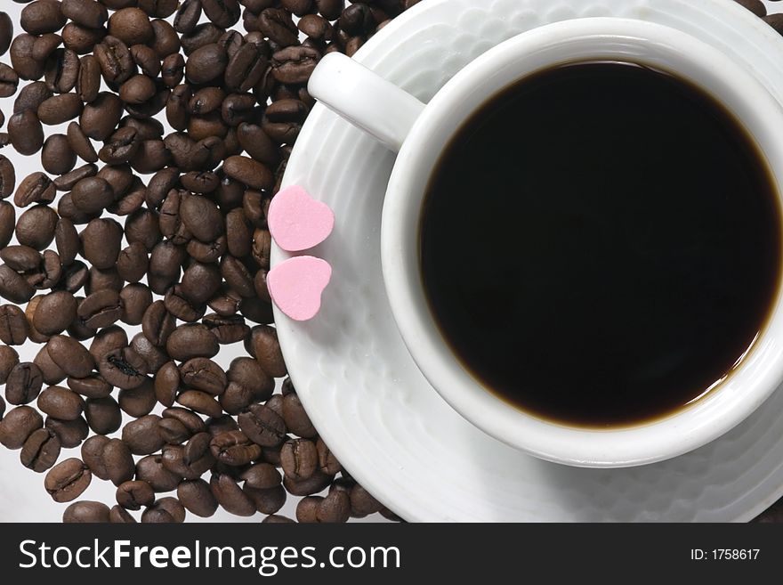 Close up of white coffee cup with coffee-beans and pink hearts. Close up of white coffee cup with coffee-beans and pink hearts