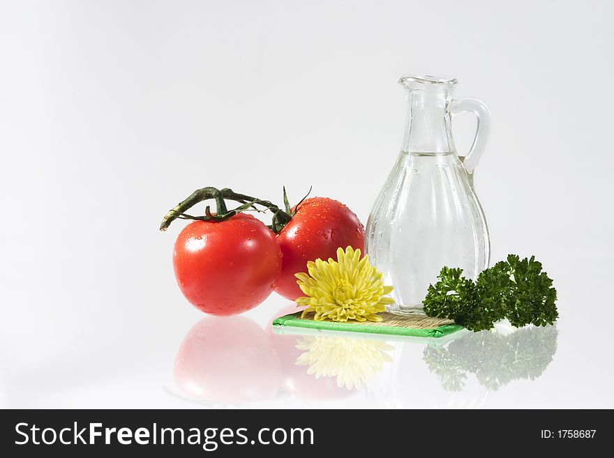 Tomatoes, yellow flower, parsley and decanter with water over white. Tomatoes, yellow flower, parsley and decanter with water over white