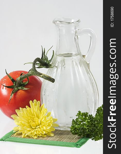 Tomatoes, yellow flower, parsley and decanter with water over white. Tomatoes, yellow flower, parsley and decanter with water over white