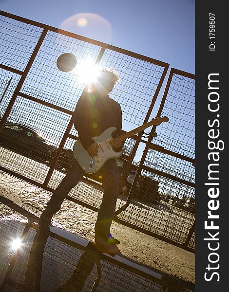Cool guy playing his guitar against sunlight. Cool guy playing his guitar against sunlight