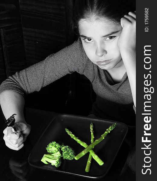 Young girl looking angry at the thought of having vegetables for dinner ~ selective Color. Young girl looking angry at the thought of having vegetables for dinner ~ selective Color.