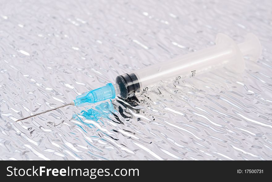 Medical syringe on a metal background