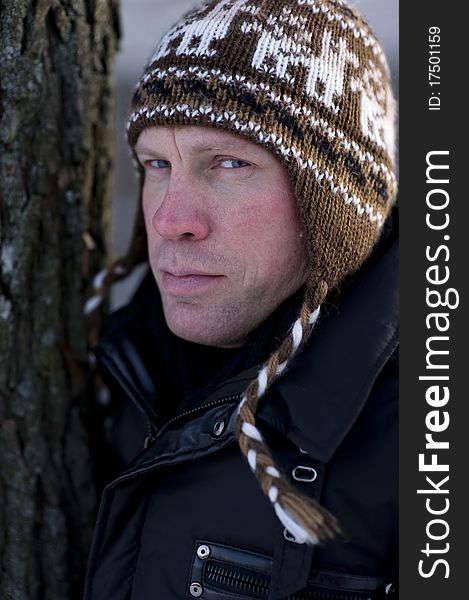 Portret of man in winter hat leaning on tree. Portret of man in winter hat leaning on tree