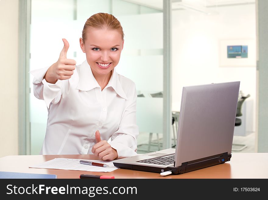 Expressive businesswoman showing thumb up on her workplace