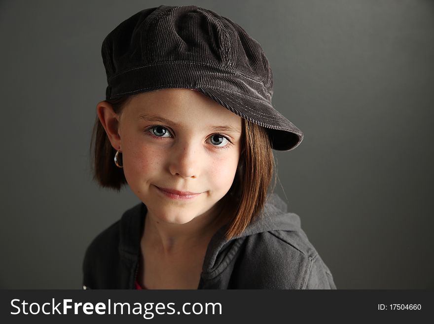 Close up of a beautiful young female child wearing a newsboy cap and hoop earrings. Close up of a beautiful young female child wearing a newsboy cap and hoop earrings