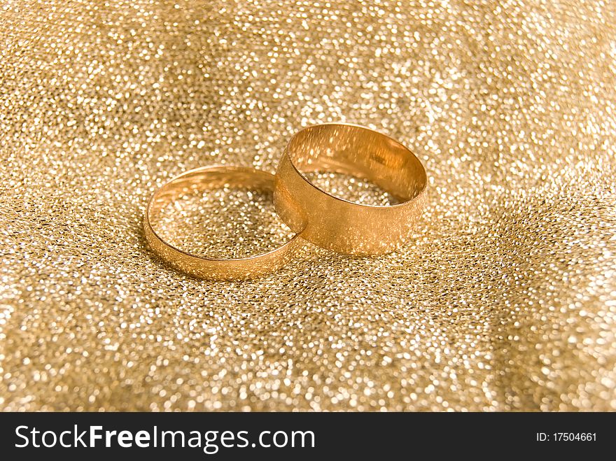 Gold wedding rings on a golden fabric background. Gold wedding rings on a golden fabric background
