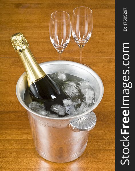 A bottle of sparkling wine is cooling in an ice bucket. A bottle of sparkling wine is cooling in an ice bucket.