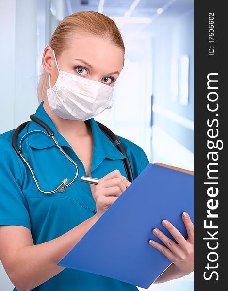 Young blond in medical gown with stethoscope and file folder in an hospital. Young blond in medical gown with stethoscope and file folder in an hospital