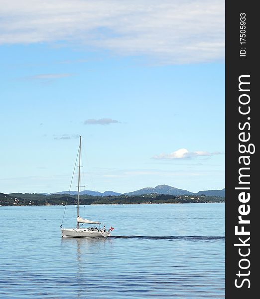 Yacht sailinng past Norway coastline near the Bergen