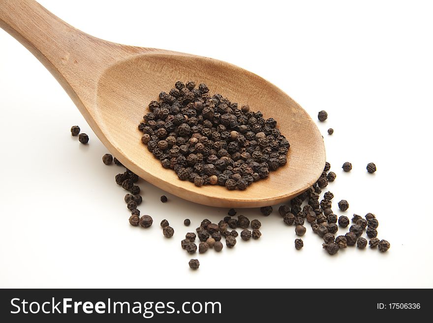 Peppercorns on wooden spoon and white background