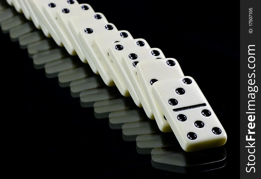 Toppled dominoes, white tiles on black background. Toppled dominoes, white tiles on black background.