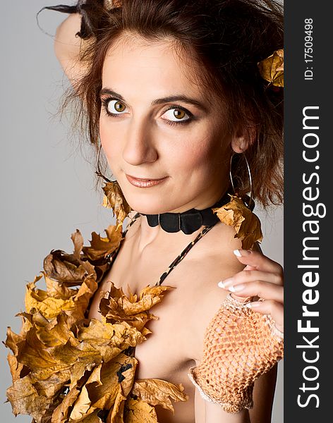 Portrait of beautiful, young girl in lingerie made of leaves. Gray background. Studio shot. Portrait of beautiful, young girl in lingerie made of leaves. Gray background. Studio shot.