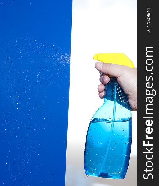 Hahd holding bottle of cleaning solution on the blue background