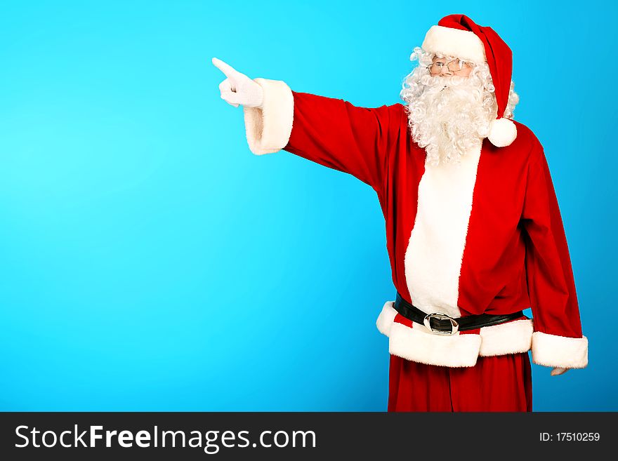 Portrait of Santa Claus pointing at something over blue background. Christmas. Portrait of Santa Claus pointing at something over blue background. Christmas.