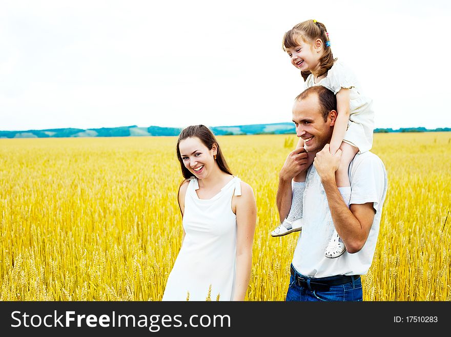 Happy family; young mother, father and their daughter having fun at the wheat field (focus on the child)