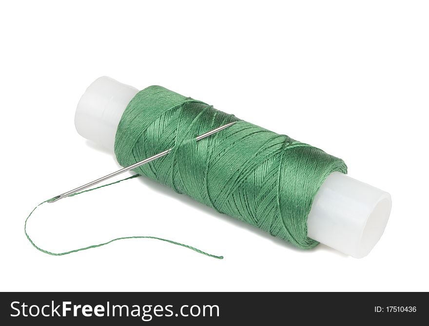 Green spool with needle on a white background