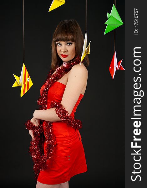 Beautiful girl in a red dress with paper fish is isolated on a black background. Beautiful girl in a red dress with paper fish is isolated on a black background