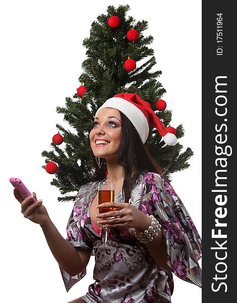Woman in a christmas hat speak mobile in front of a christmas tree. Woman in a christmas hat speak mobile in front of a christmas tree
