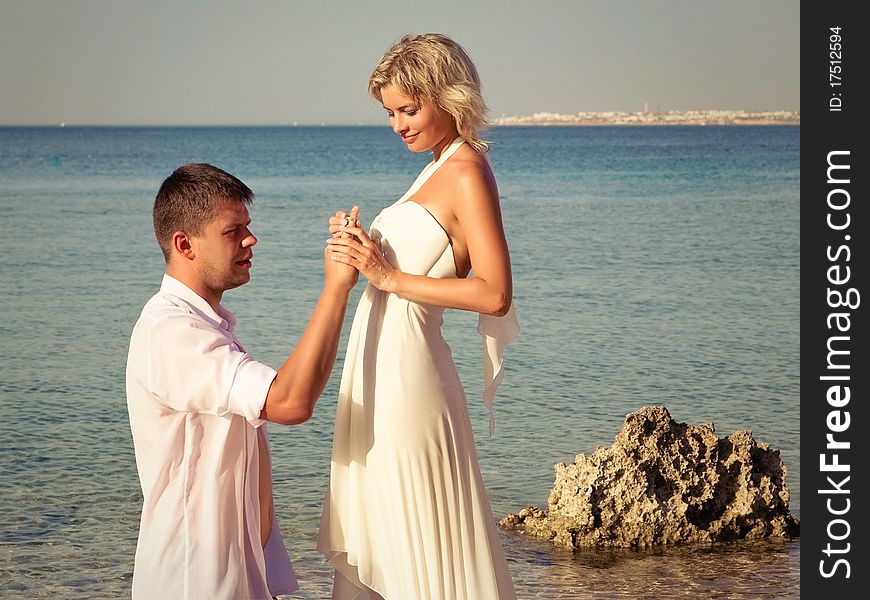 Groom wears ring bride on beach