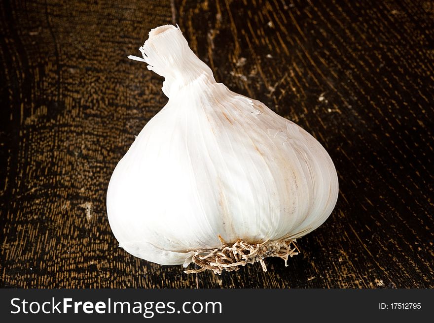 Single garlic bulb lying on a wooden tray