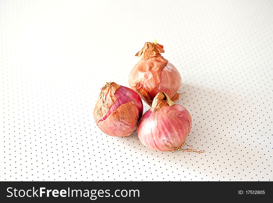 Three unpeeled shallots lying on a polka dotted backdrop